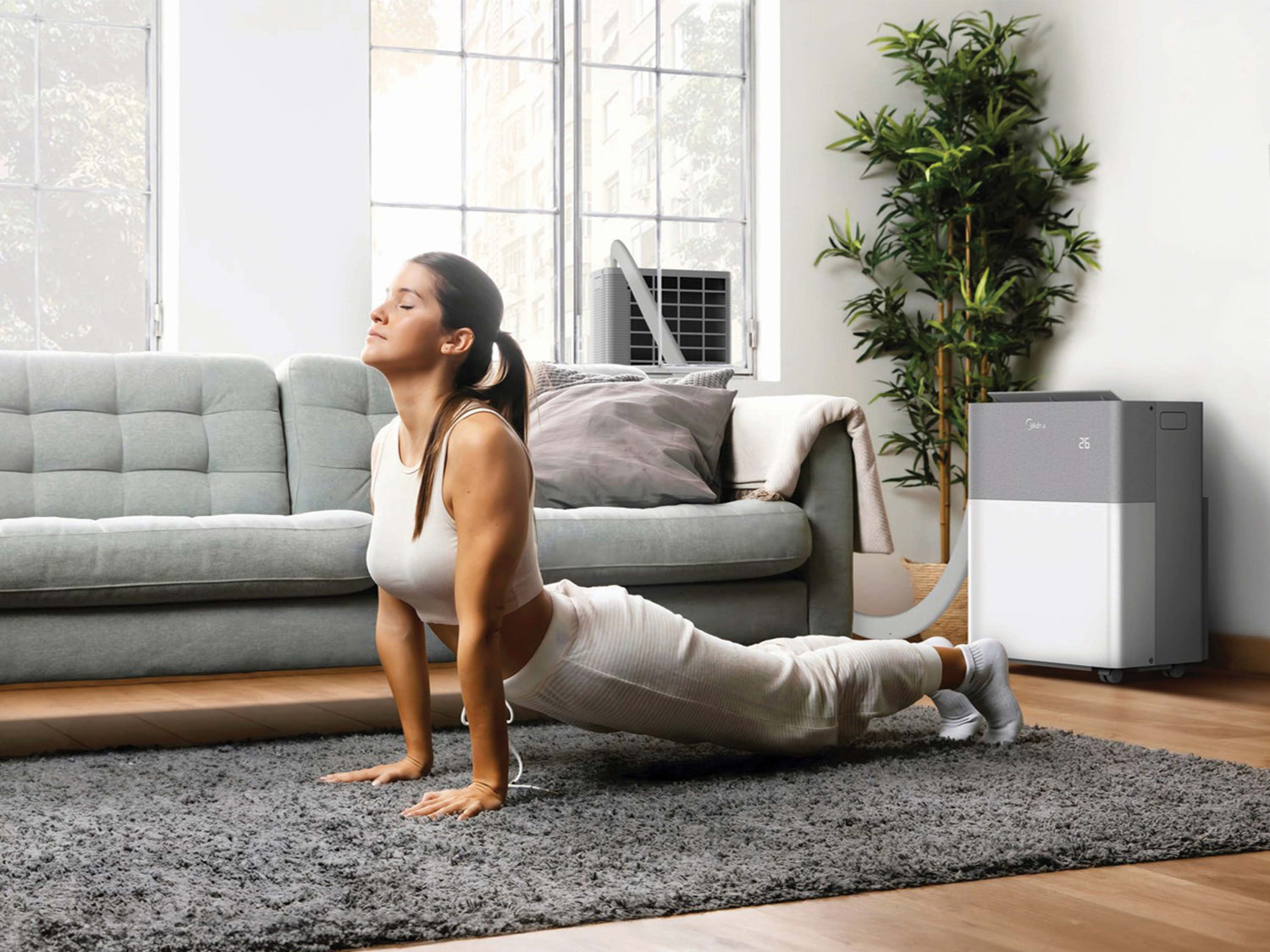 Woman exercising on a rug in a living room with quiet and non disturbing air conditioning in the corner.