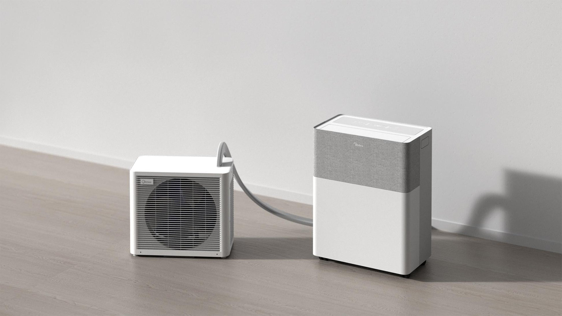 Two white air conditioning units on a wooden floor with a plain wall background
